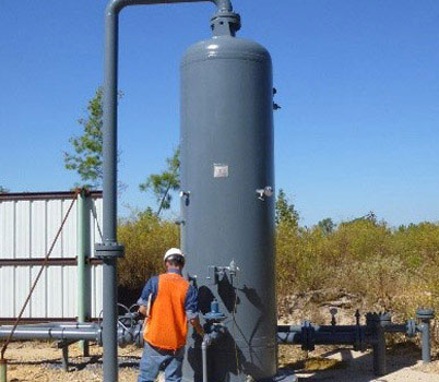 Man standing beside large tank. 