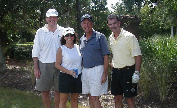 four people in a row, playing golf