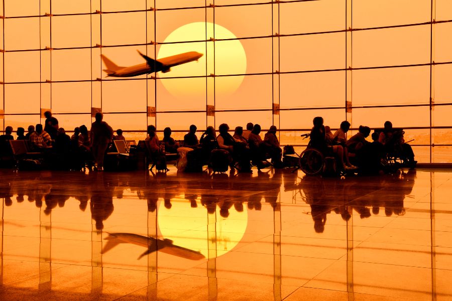 Airport gate with people waiting and plane in backround.