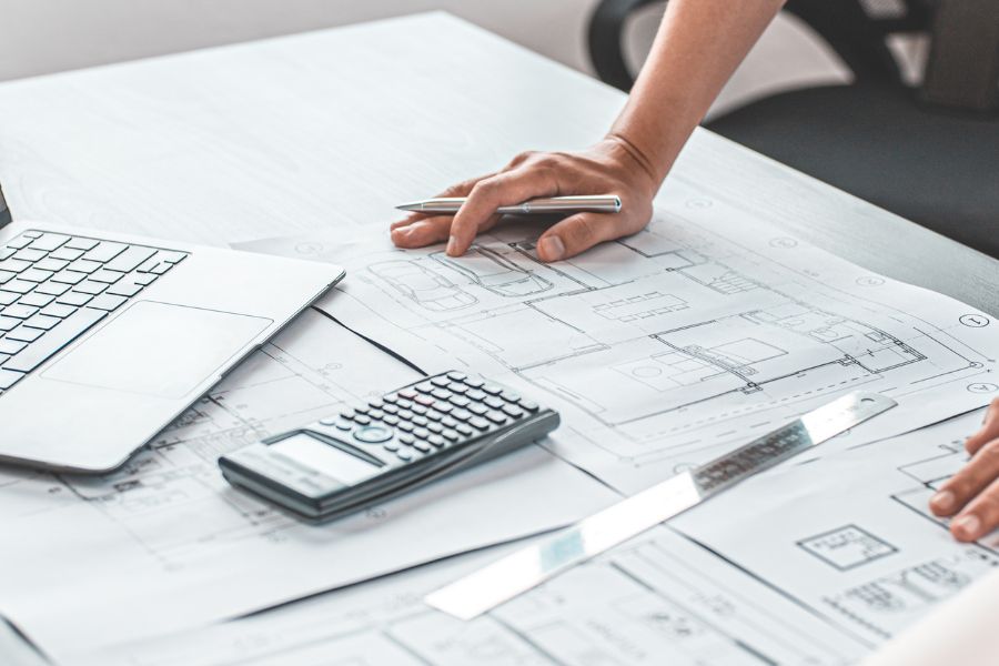 Architectural plans with a calculator and laptop.