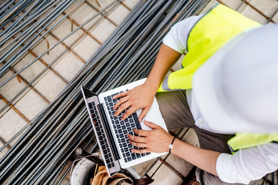 Man on laptop at construction site.