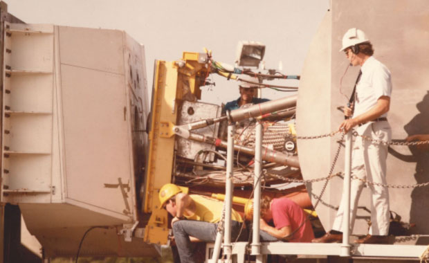 Three people working on equipment. 