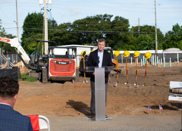 Dawn Aiello speaking at Aspire groundbreaking, construction site with machinery and helmets.