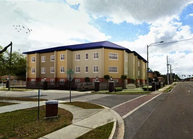 Three-story beige building with a blue roof, located at a street corner.
