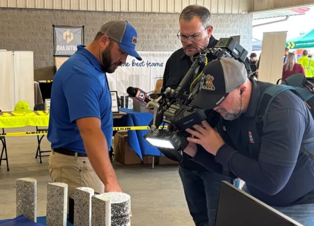 Brent Wilkins closely examines concrete samples during an interview recording in an industrial setting