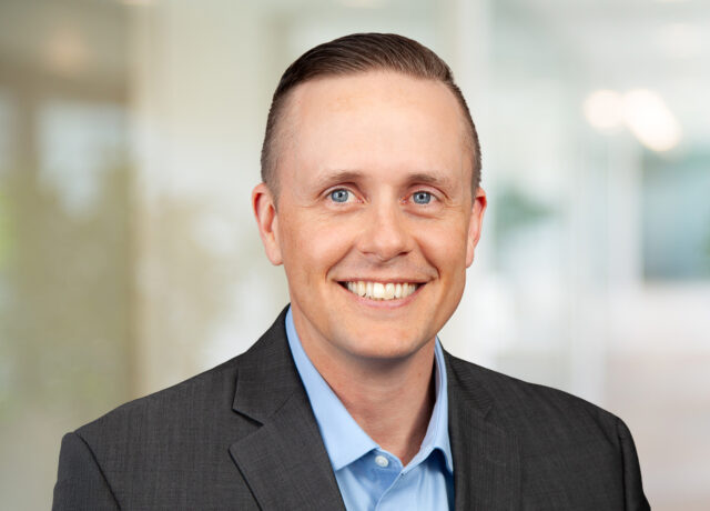 Cundiff Ray smiling in a suit, blurred office background