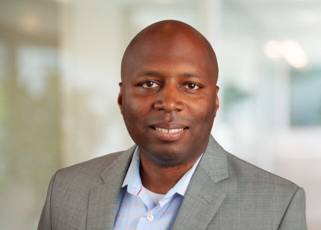 Haywood Jeremy smiling in a professional gray suit with a blurred office background