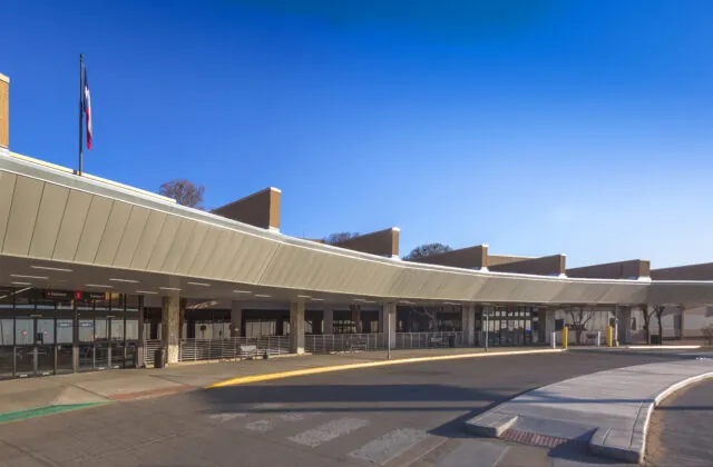 Entrance to modern building with Texas flag, blue sky