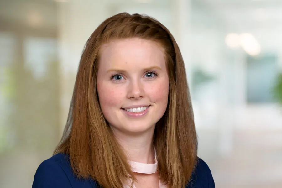 Julie Warner smiling, wearing a blue jacket and pink blouse, office background