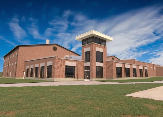 Brick building with large windows and central tower under a blue sky