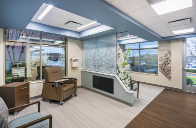 Modern medical waiting room with large windows, beige and brown decor, and comfortable seating