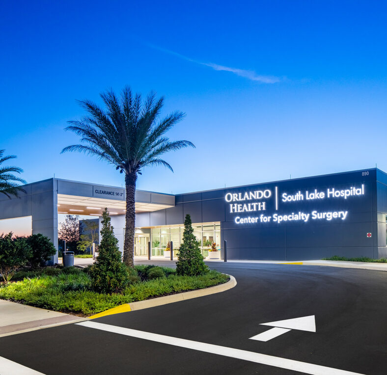 Orlando Health South Lake Hospital entrance at dusk, with palm trees and signage for Center for Specialty Surgery