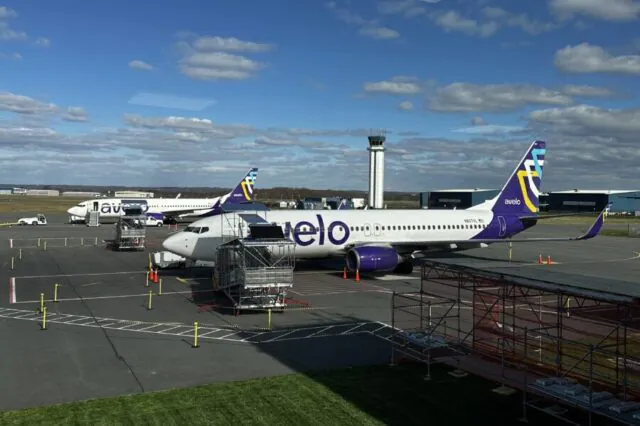 Avelo Airlines planes parked at an airport with a control tower.