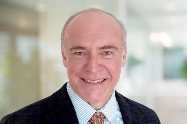 Fabio Bendana smiling in an office setting wearing a suit and tie