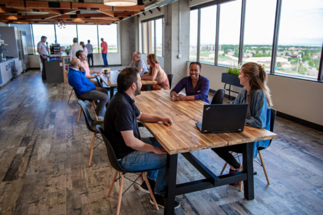 People working and socializing in a modern office lounge with city views