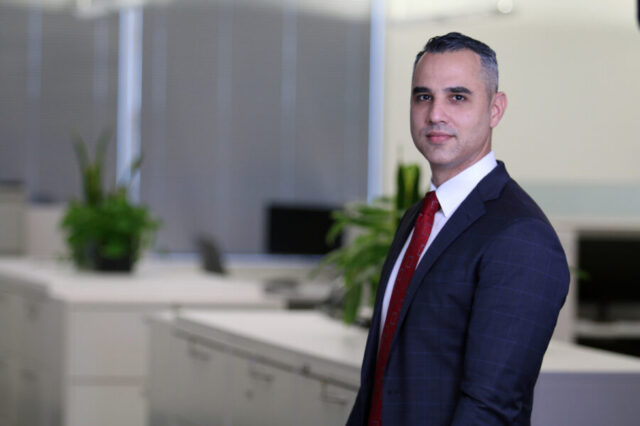 Esteban Gonzalez wearing a suit smiles in an office environment