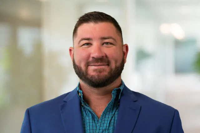 Brent Wilkins smiling in a blue blazer and checkered shirt