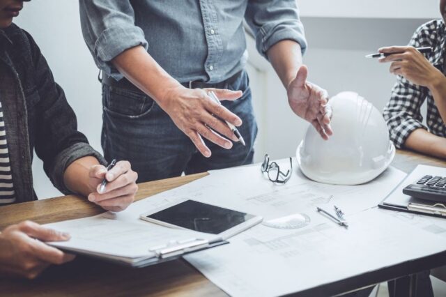People working at a desk with ipad and construction plans.