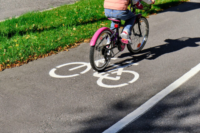 Child cycling on path with bicycle symbol, green grass beside path