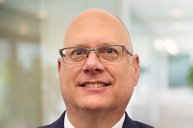 Matthew Kunath smiling, wearing glasses, in an office setting.