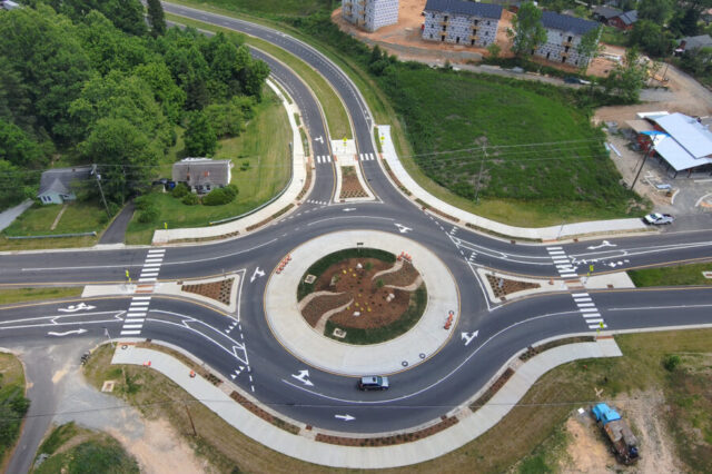 Aerial view of a roundabout with road markings and surrounding greenery