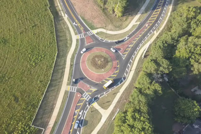 Aerial view of a roundabout with bike and pedestrian lanes, surrounded by greenery.