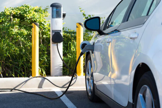 Electric car charging at a public charging station surrounded by greenery