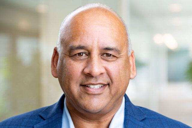 Rahman Anees smiling in a blue suit jacket, indoor setting