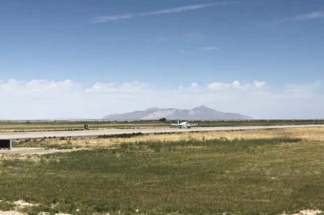 Small airplane on runway with mountains in the background under a clear sky