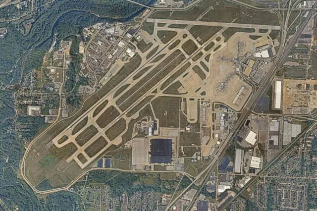 Aerial view of a large airport with multiple runways and surrounding buildings.