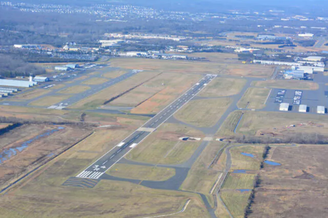 Aerial view of Manassas airport runway extension surrounded by fields and hangars.
