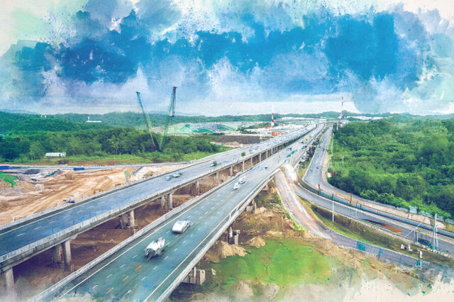 Elevated highway construction with cranes, surrounded by lush greenery and cloudy sky.