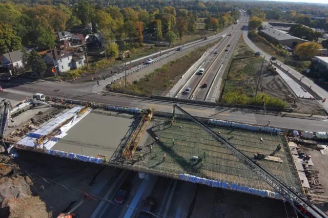 Bridge construction underway over a highway with vehicles passing beneath