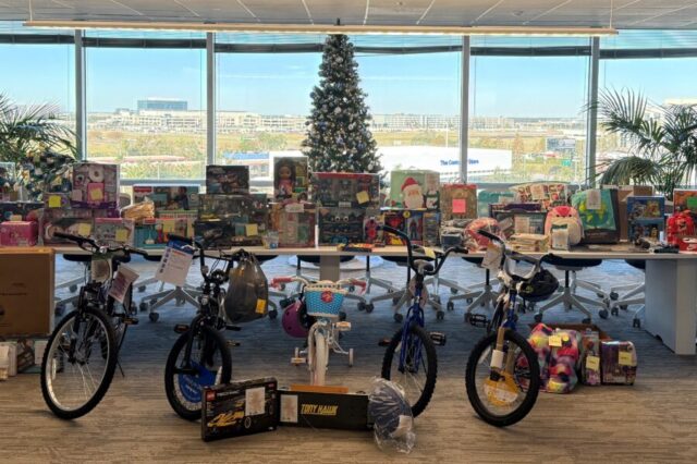 Bicycles and toys arranged under a decorated Christmas tree in an office setting.